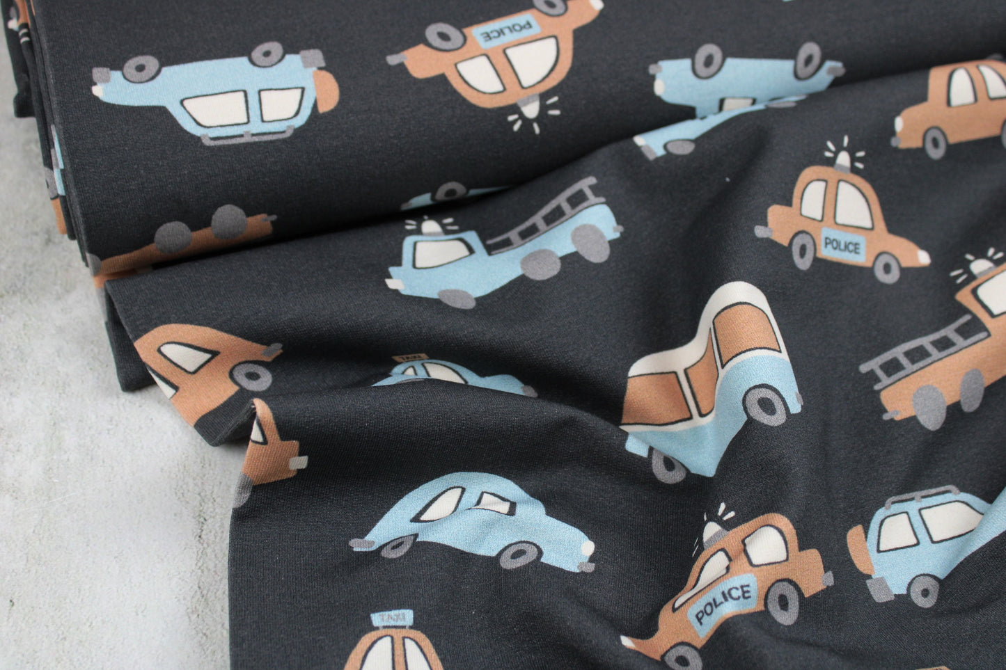 Dunkelgrauer Kinderstoff mit Autos in beige und hellblau für Kinderbekleidung Ballenansicht