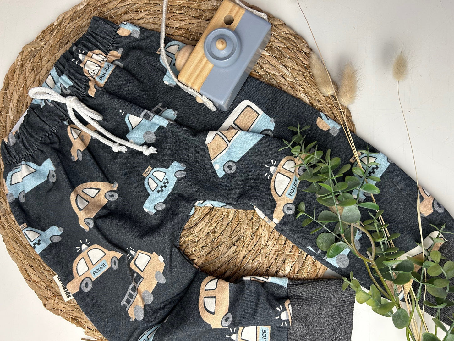Dunkelgrauer Kinderstoff mit Autos in beige und hellblau für Kinderbekleidung also Hose vernäht