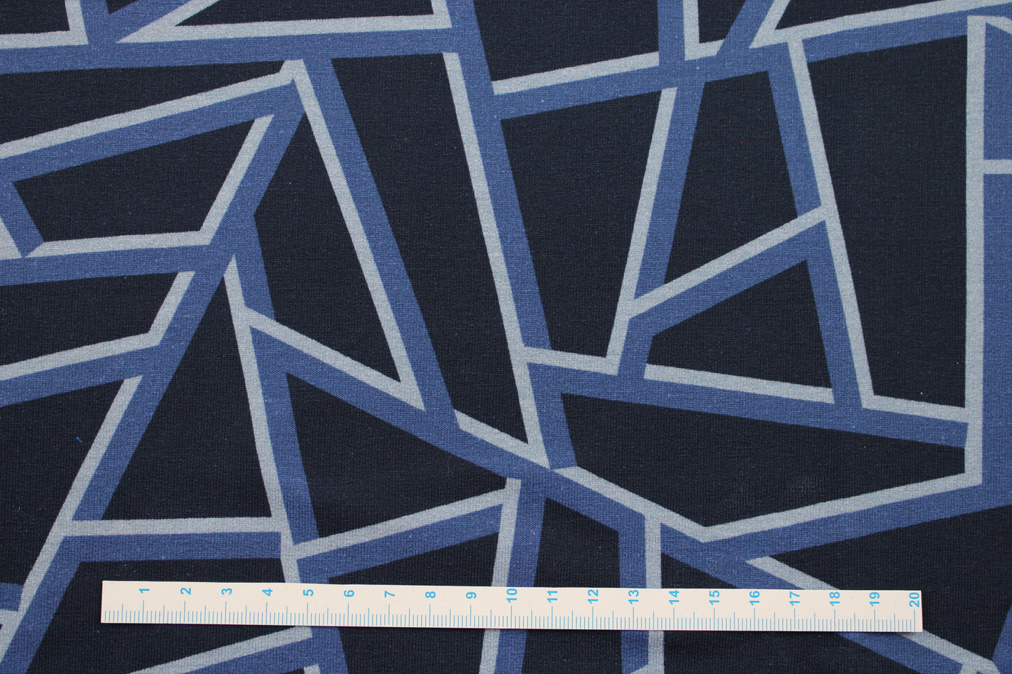Dunkelblauer Sweatstoff mit blauen geometrischen Mustern Maßstab