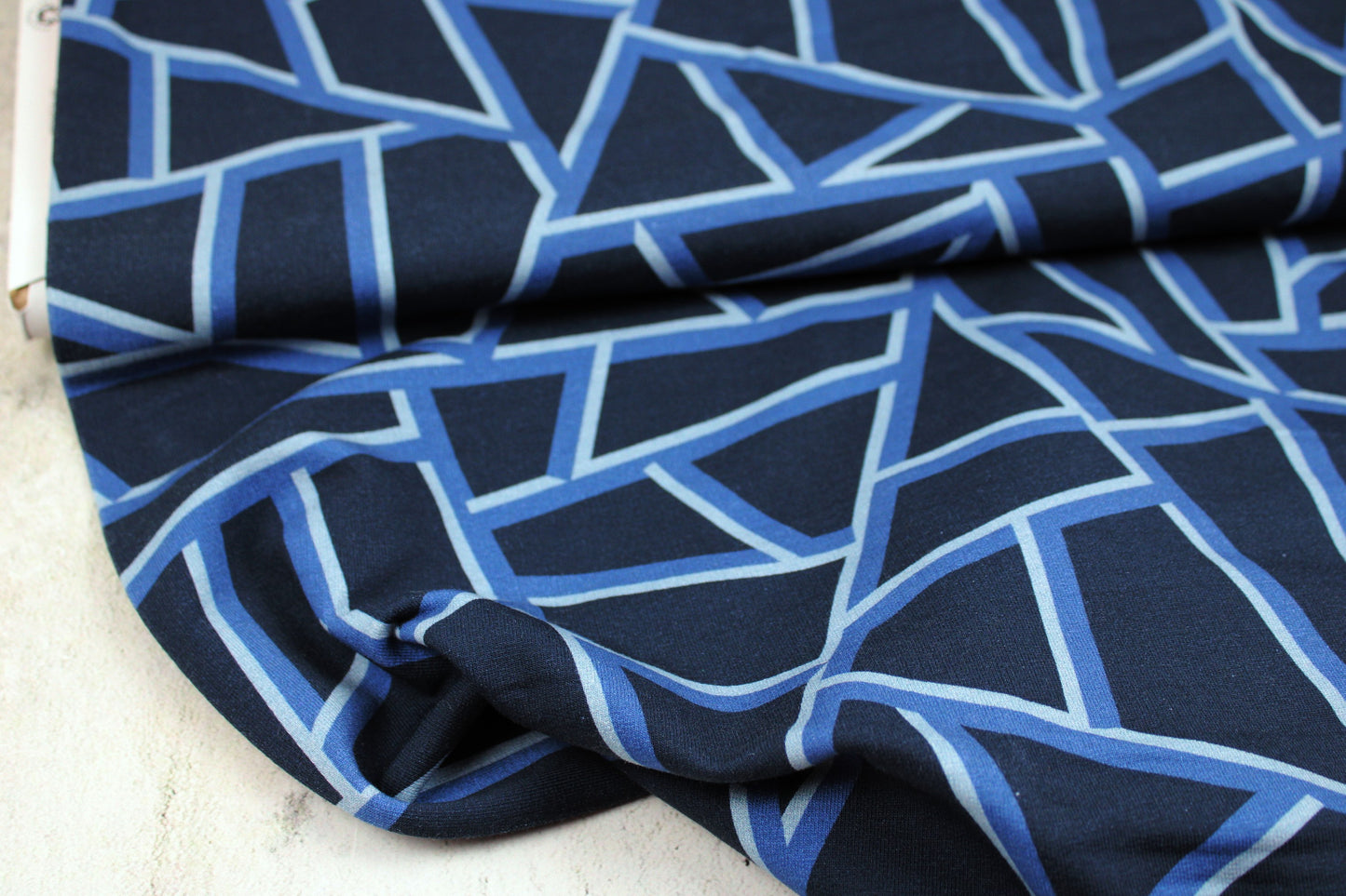 Dunkelblauer Sweatstoff mit blauen geometrischen Mustern Ballenansicht