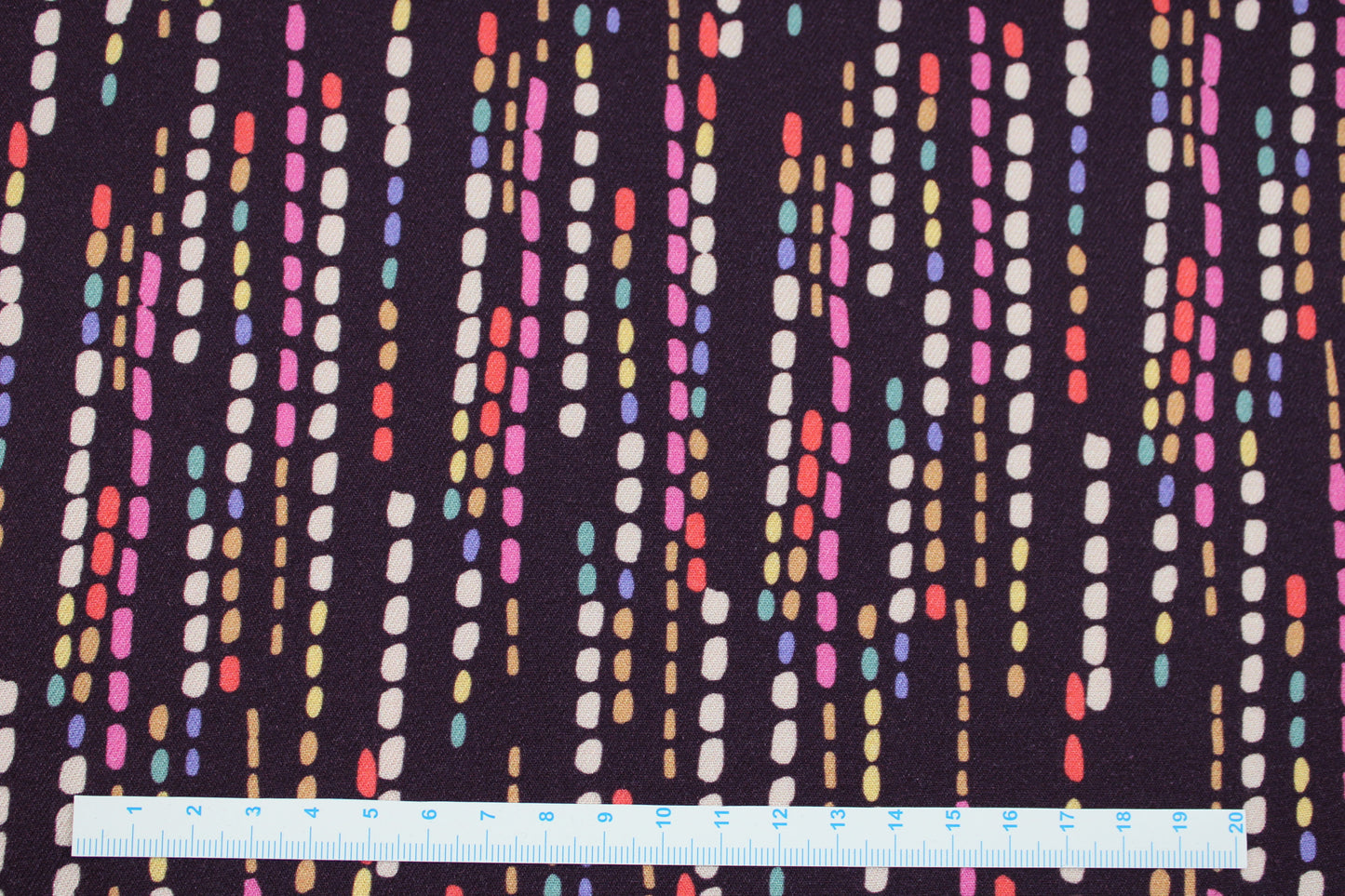 Violetter Viskosestoff mit bunten Punktelinien Maßstab