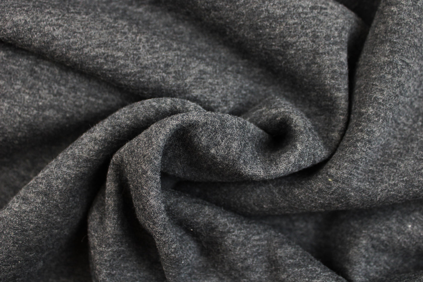 Melierter Alpenfleece Stoff in dunkelgrau mit weißer Fleeceabseite gedreht