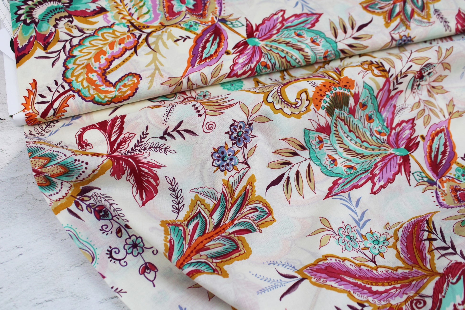 Baumwollbatist mit buntem Paisley-Blumenmuster auf wollweißem Grund Ballenansicht