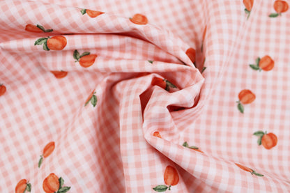 Baumwollstoff Fruta kleine Früchte auf orange-weiß kariertem Grund gedreht