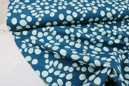 Baumwolljersey Fine Eukalyptus mit kleinen mintfarbenen Blättern auf petrol Grund Ballenansicht