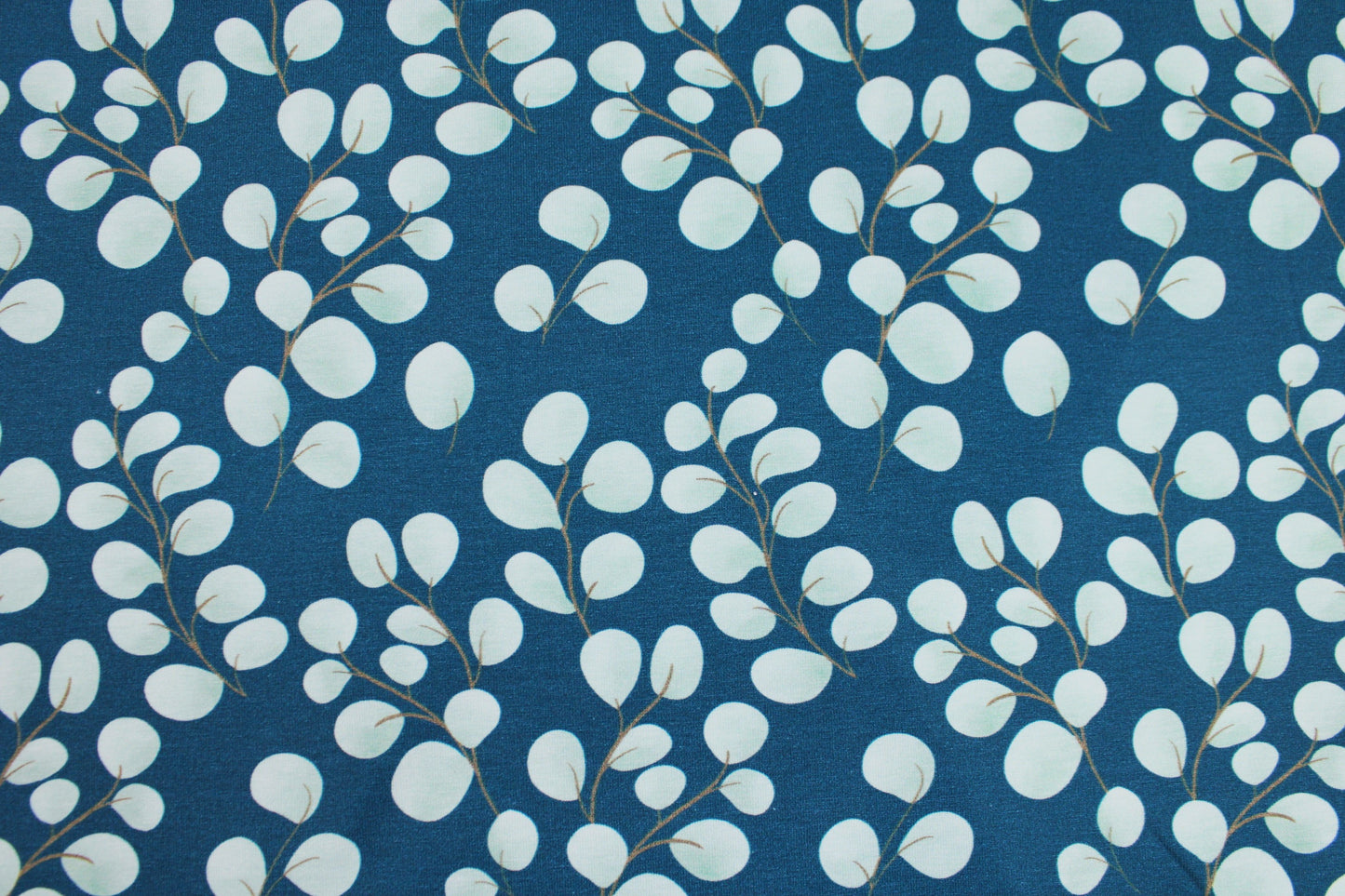 Baumwolljersey Fine Eukalyptus mit kleinen mintfarbenen Blättern auf petrol Grund Detailbild