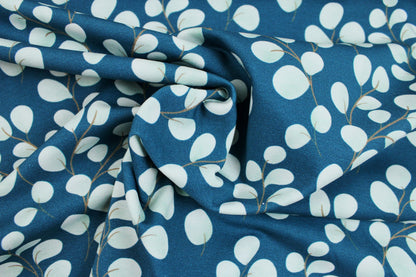 Baumwolljersey Fine Eukalyptus mit kleinen mintfarbenen Blättern auf petrol Grund gedreht