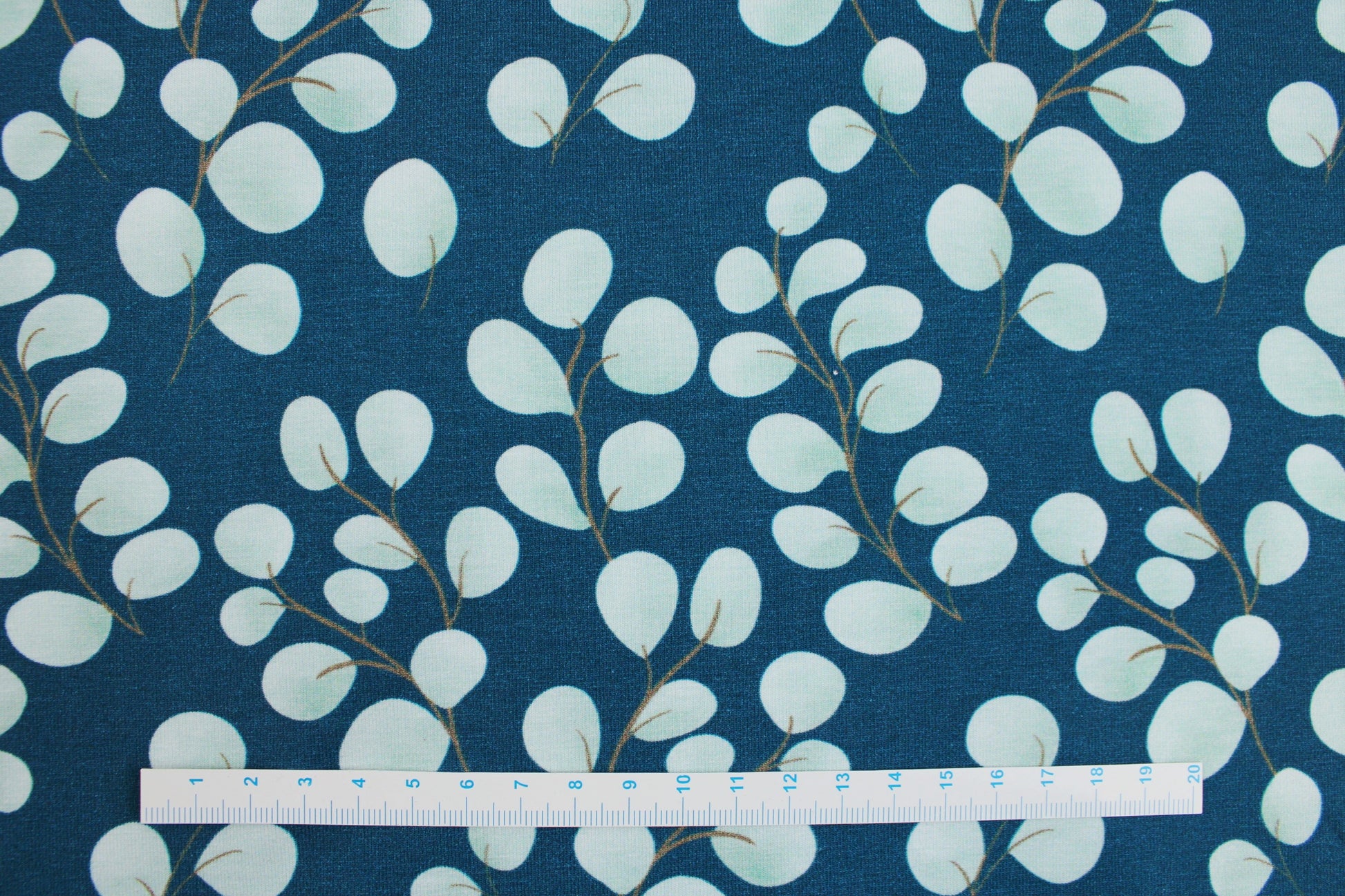 Baumwolljersey Fine Eukalyptus mit kleinen mintfarbenen Blättern auf petrol Grund Maßstab