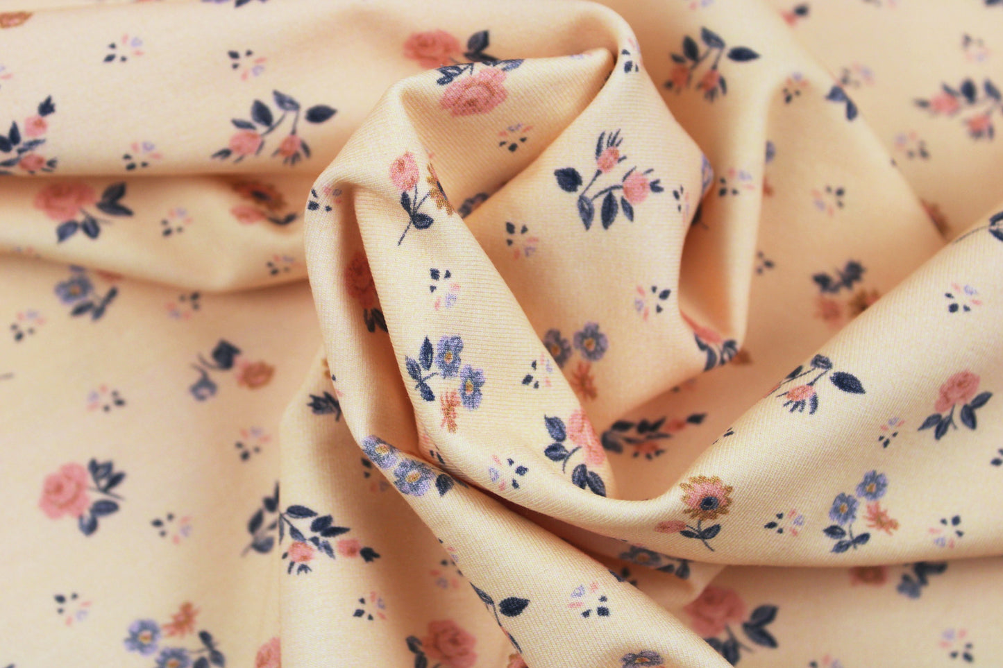 Baumwolljersey Flowers & Wood mit zarten Blümchen auf Creme farbenem Grund gedreht