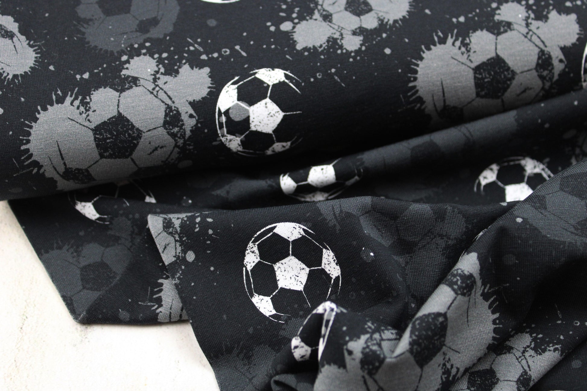 Schwarzer Baumwolljersey mit Fußball-Motiv in grau und weiß Ballenansicht