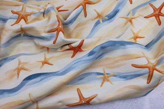 Baumwolljersey Strandspaziergang mit Seesternen in Blau- und Gelbönen