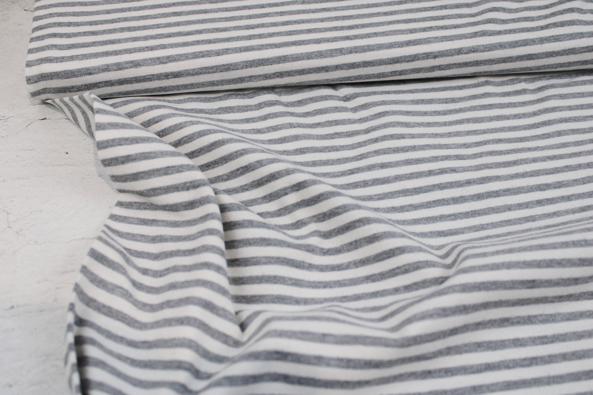 Weicher Baumwolljersey mit dünnen Streifen in Grau meliert und Wollweiß Ballenansicht
