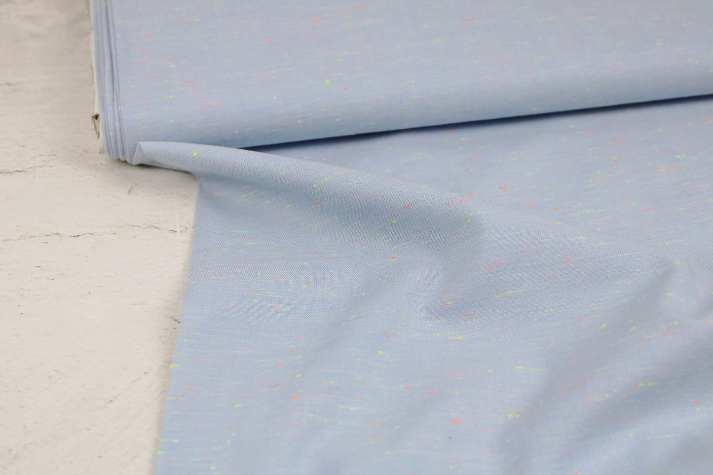 Baumwollstoff in Hellblau mit kleinen Neonfäden in Orange und Gelb Ballenansicht