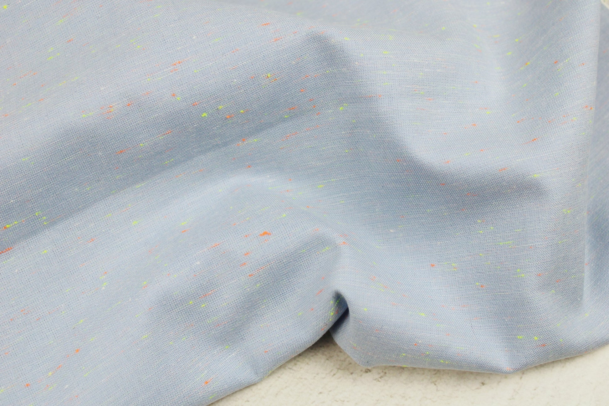 Baumwollstoff in Hellblau mit kleinen Neonfäden in Orange und Gelb