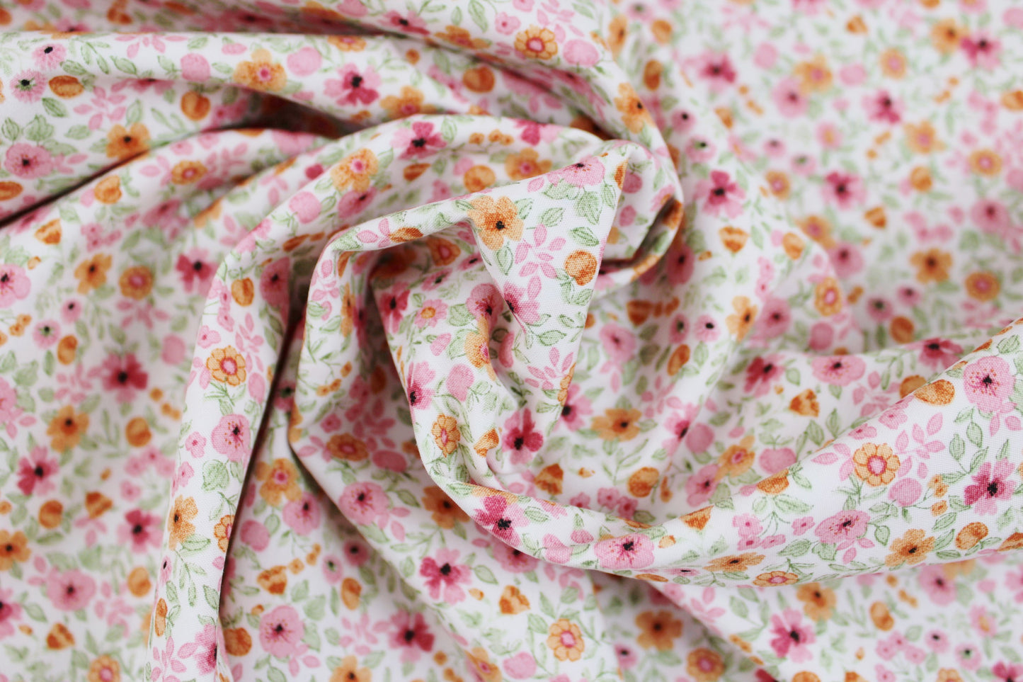 Baumwollstoff Natura mit kleinen Blümchen in Rosa und Orange gedreht