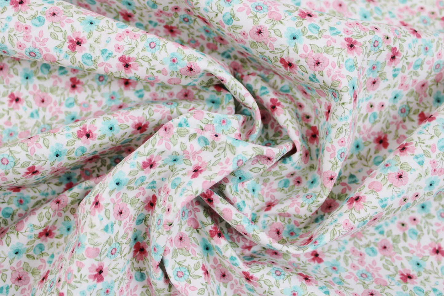 Baumwollstoff Natura mit kleinen Blümchen in Rosa und Türkis gedreht