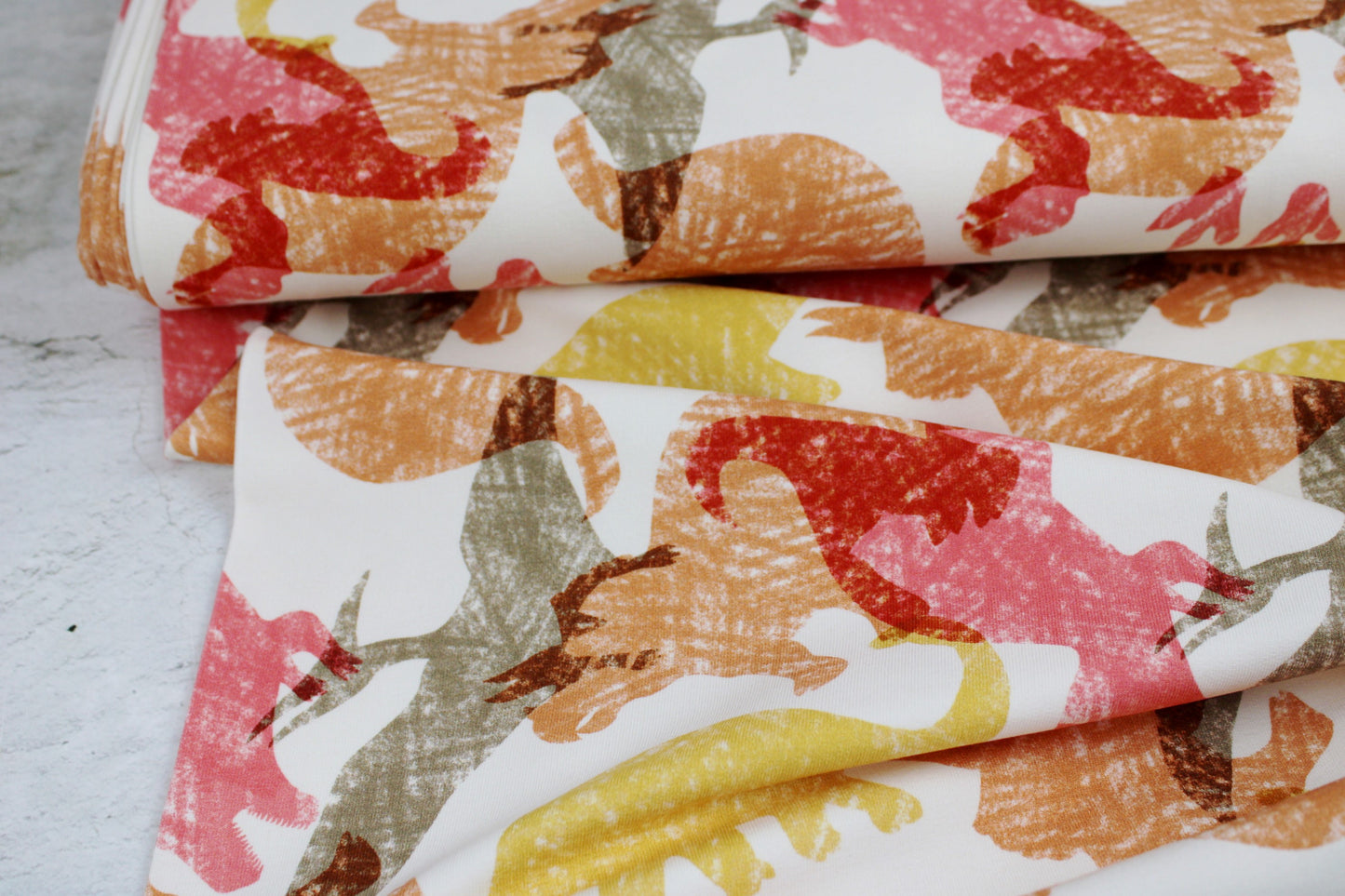 Heller French Terry Sweat mit Dinosauriern in Rot, Gelb und Orange Ballenansicht