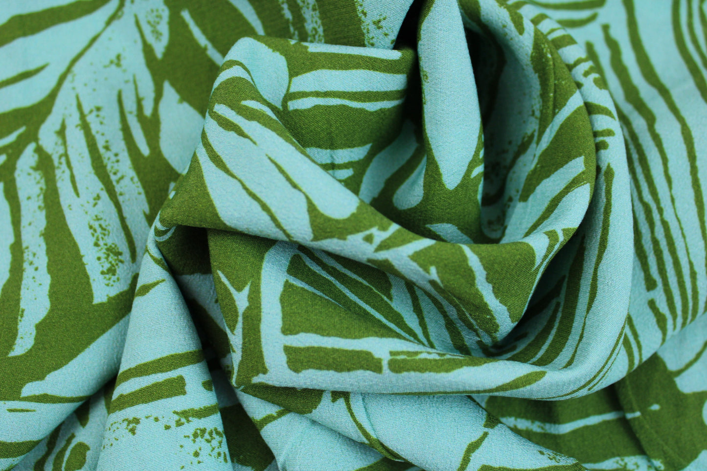 Leichter Viskosecrepestoff mit Blättermotiv in Oliv und Mint gedreht