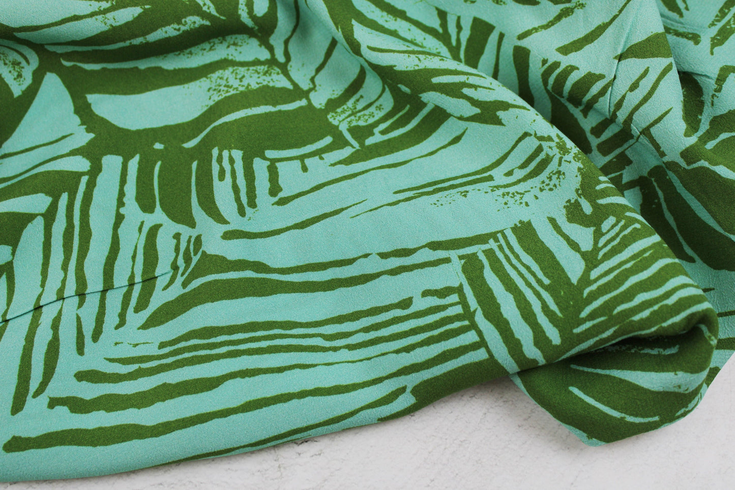 Leichter Viskosecrepestoff mit Blättermotiv in Oliv und Mint