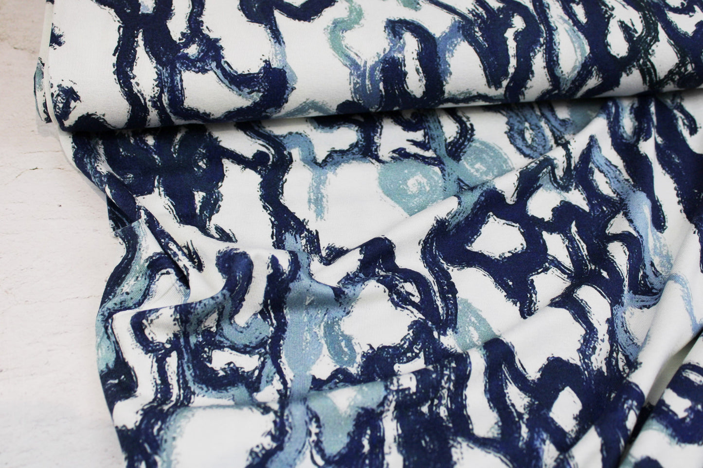 Viskosejersey mit abstrakten Linien in Blau auf weißem Grund Ballenansicht