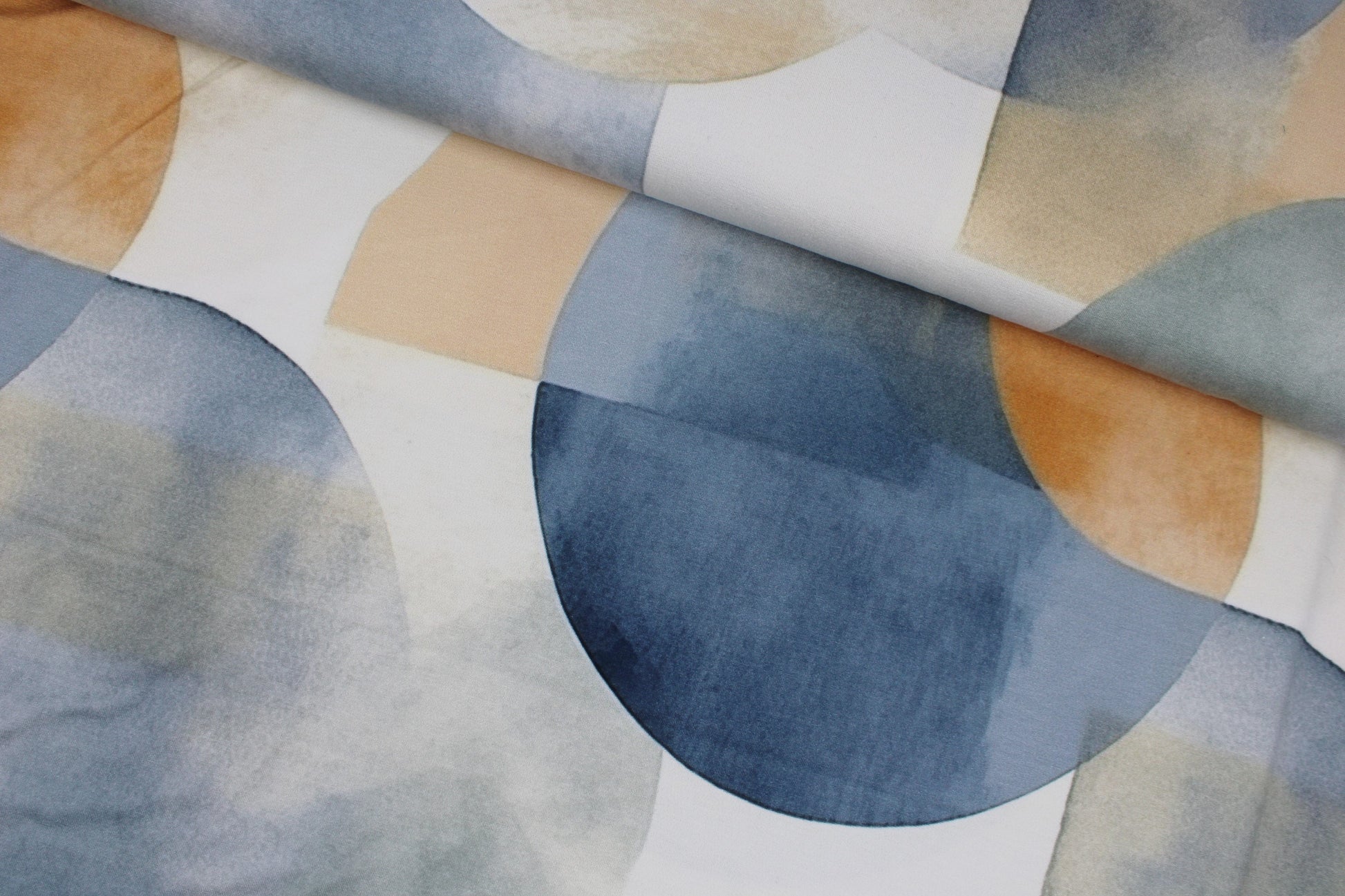 Viskosejersey mit großen geometrischen Formen in Blau und Rost auf hellem Grund quer