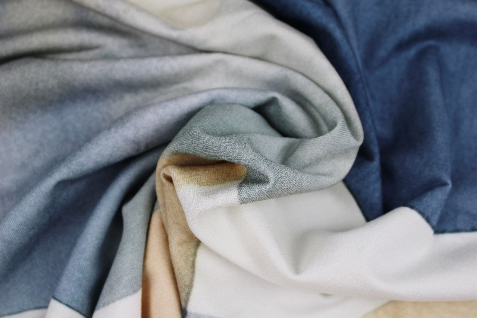 Viskosejersey mit großen geometrischen Formen in Blau und Rost auf hellem Grund gedreht