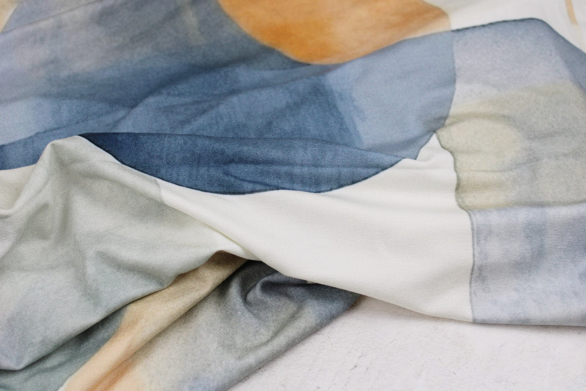Viskosejersey mit großen geometrischen Formen in Blau und Rost auf hellem Grund
