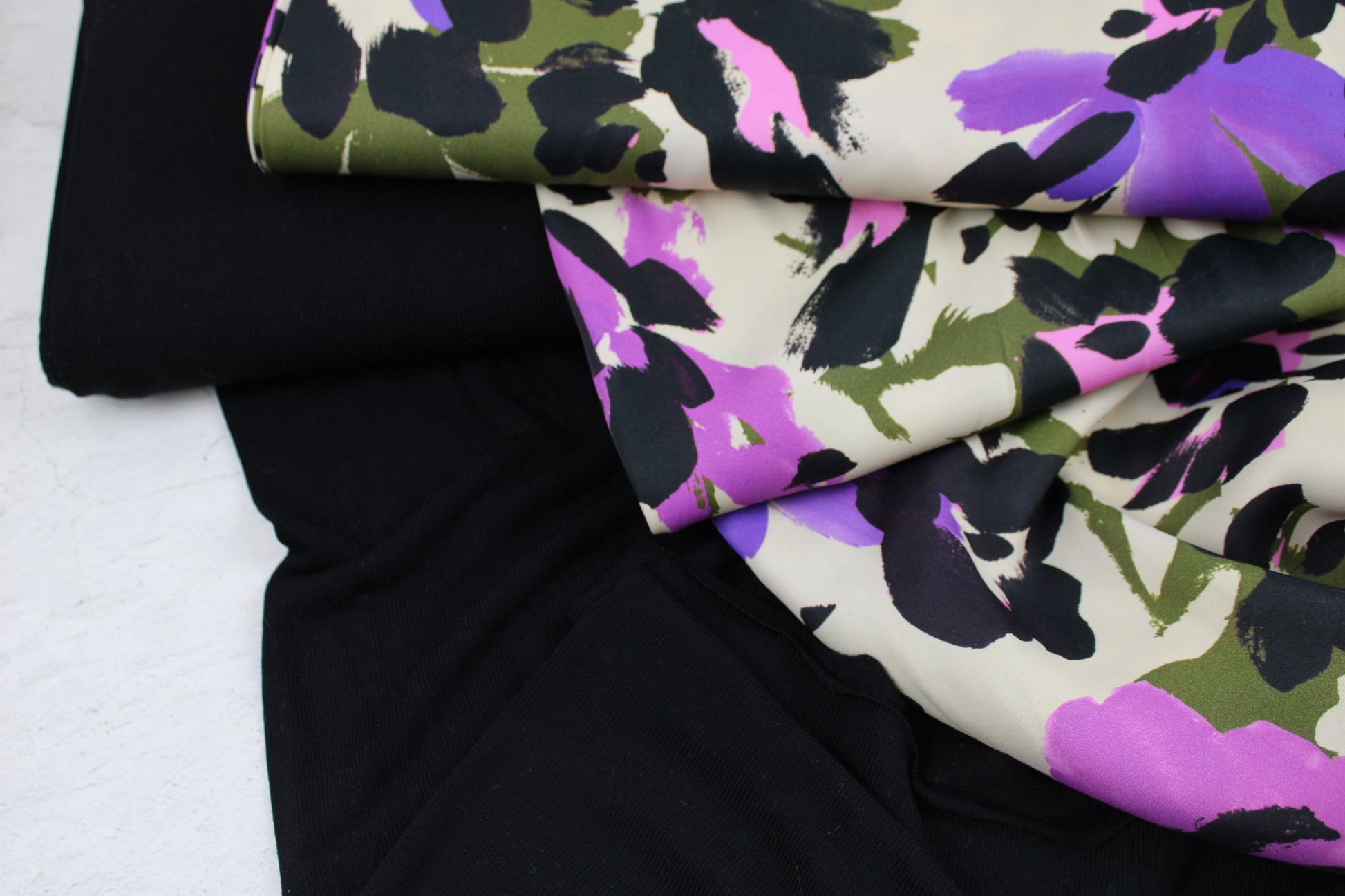 Satinierter Viskosestoff mit buntem abstraktem Blumenmuster mit schwarzem Viskosejersey