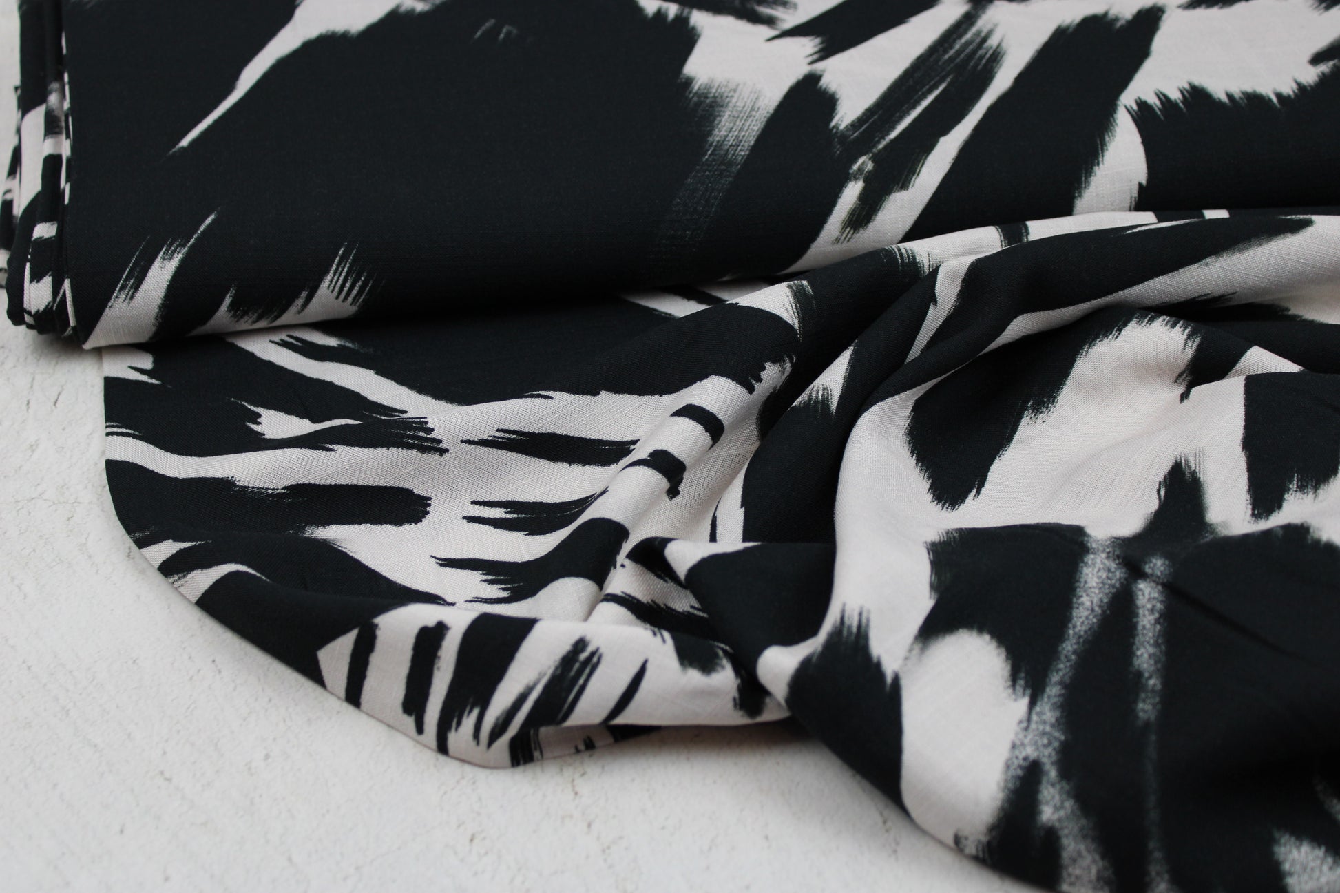 Leicht fließender Viskosestoff mit Pinselstrichmuster in Schwarz-Ecru Ballenansicht