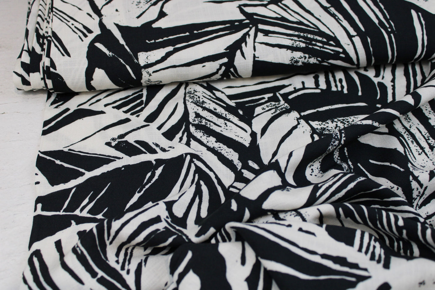 Viskosestoff mit Blättermuster und Leinenstruktur in Schwarz und Wollweiß Ballenansicht