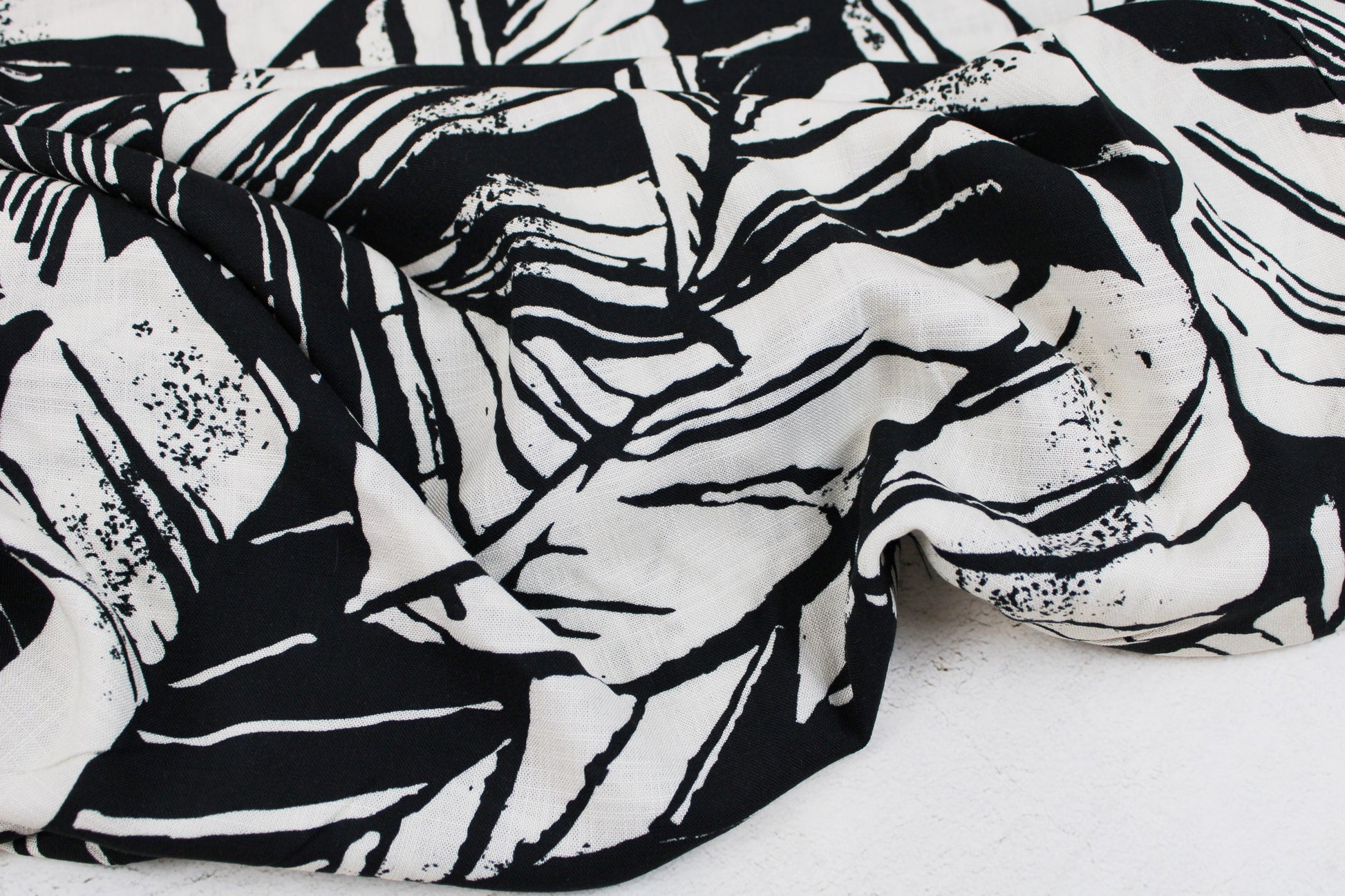 Viskosestoff mit Blättermuster und Leinenstruktur in Schwarz und Wollweiß