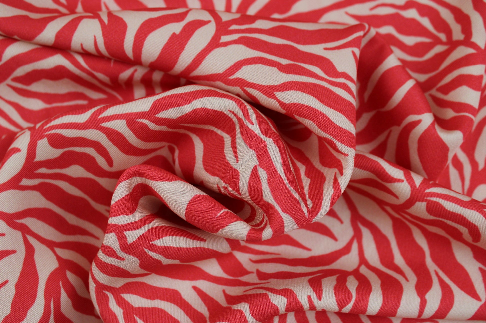 Viskosestoff Zebra Jungle mit Blätterprint in Koralle und Ecru gedreht